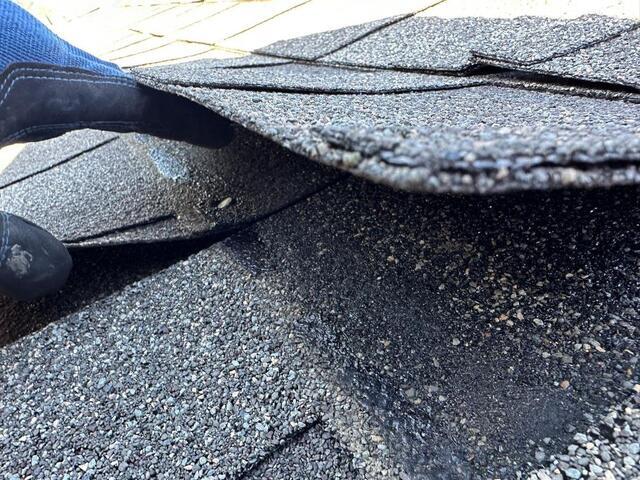 Damaged asphalt shingles on residential roof showing wear and deterioration