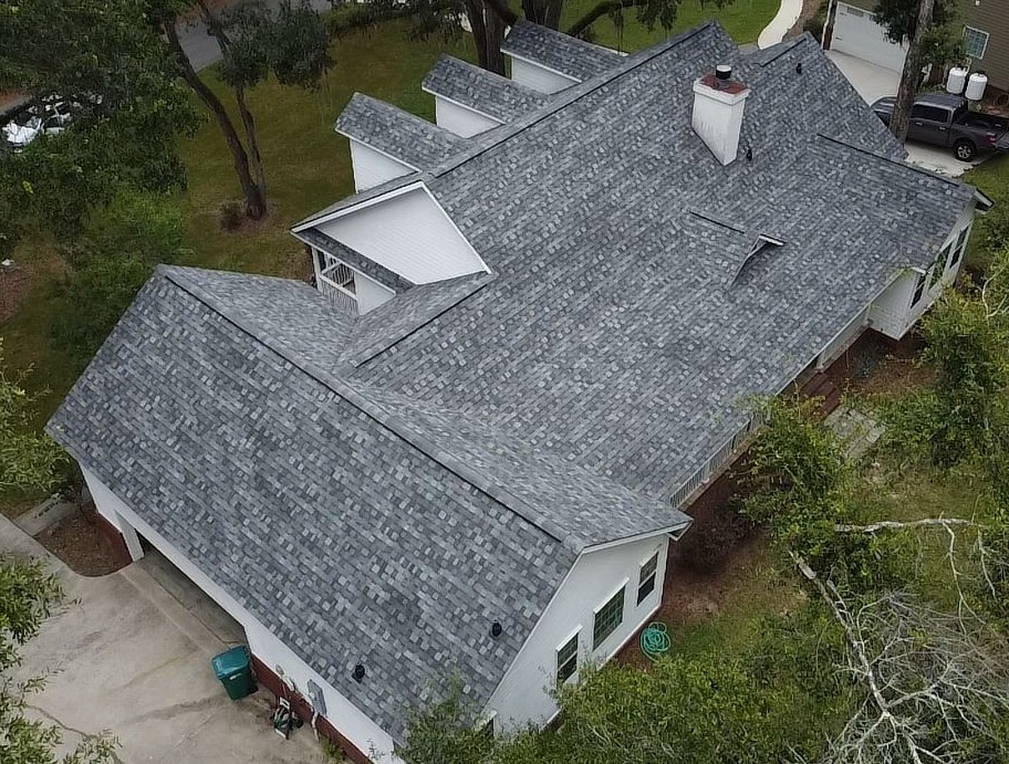 Aerial view of modern house with gray shingle roof and white exterior walls