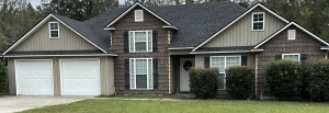 Two-story suburban home with mixed siding, two-car garage, and landscaped front yard