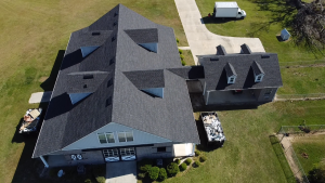 Aerial view of large residential home with dark gray roof and detached garage