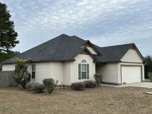 Single story beige vinyl siding house with gray shingle roof and attached garage