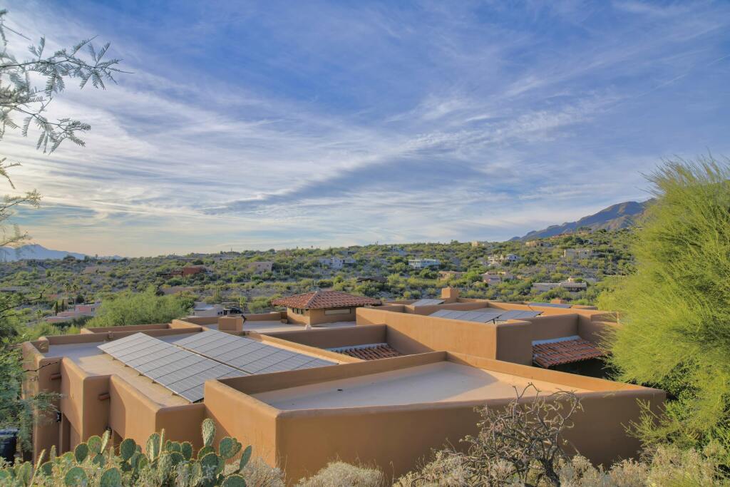 Modern adobe-style home with solar panels nestled in desert landscape with mountains