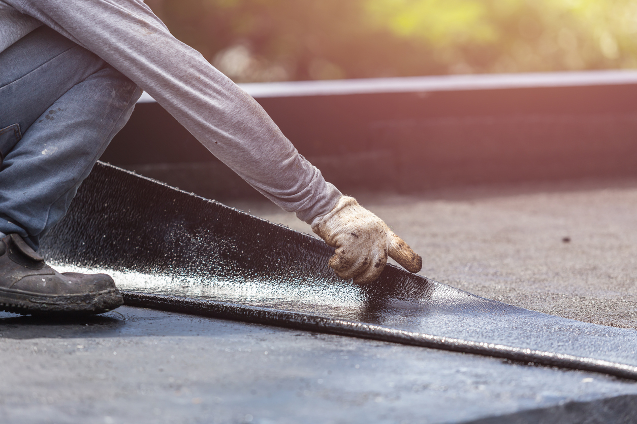 Worker applying waterproof membrane to roof surface during construction project