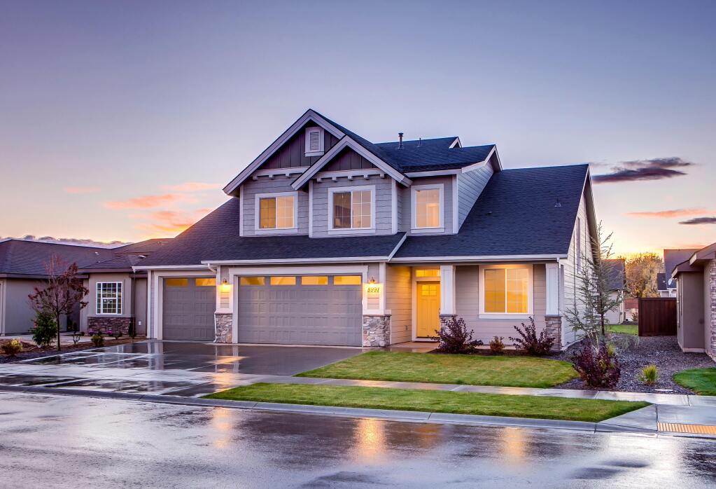 Modern two-story suburban house with gray siding and stone accents at twilight