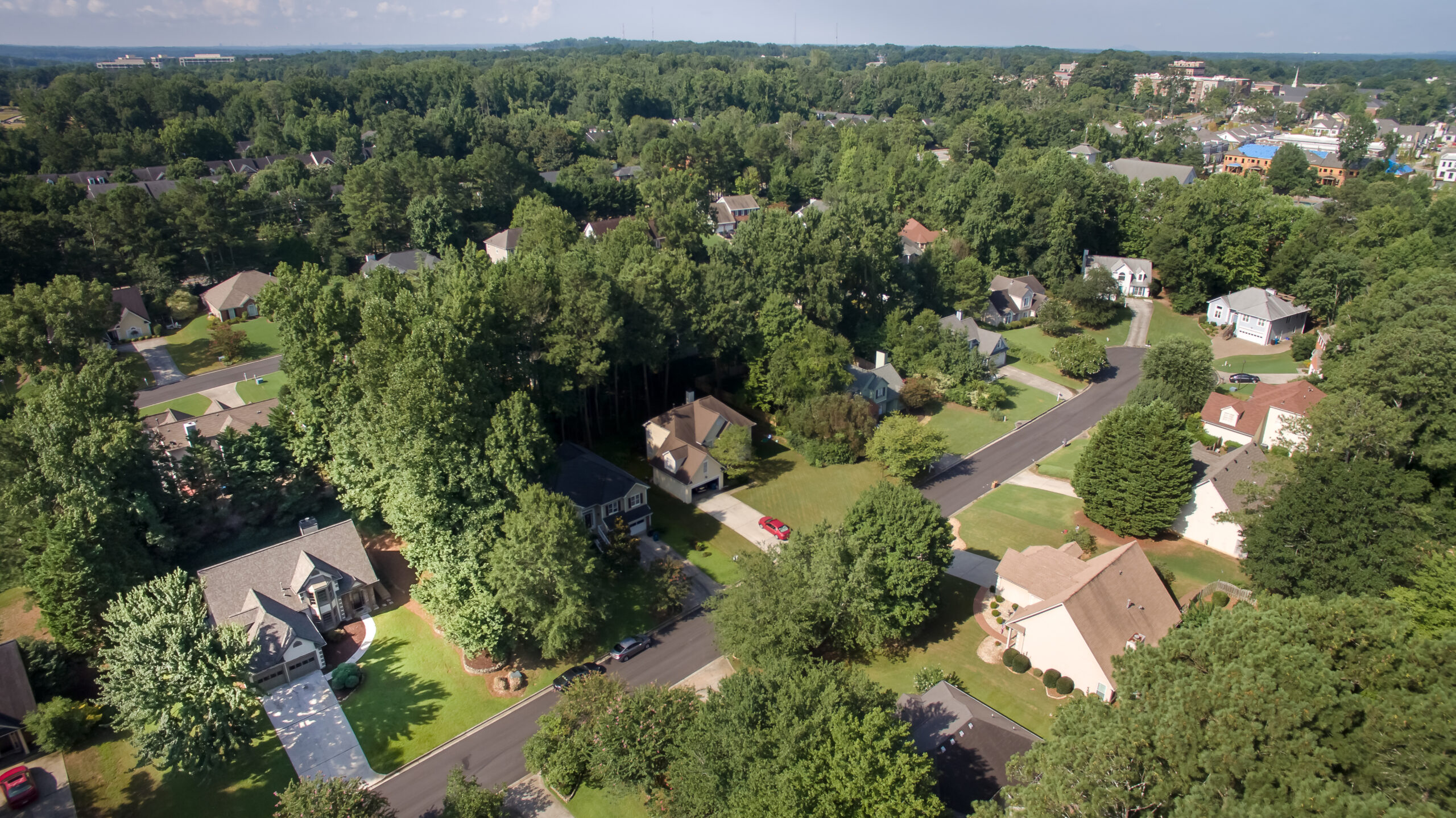 Aerial view of suburban neighborhood with houses surrounded by lush green trees