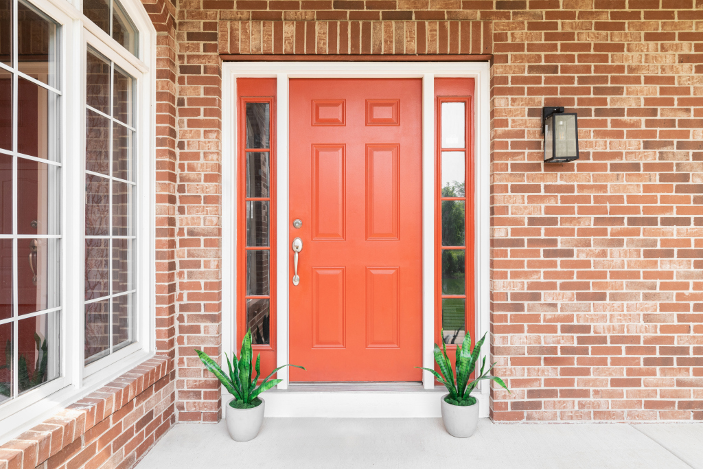 Vibrant red front door with brick walls and potted plants