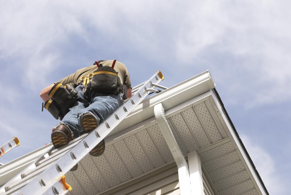 Man on ladder working on roof