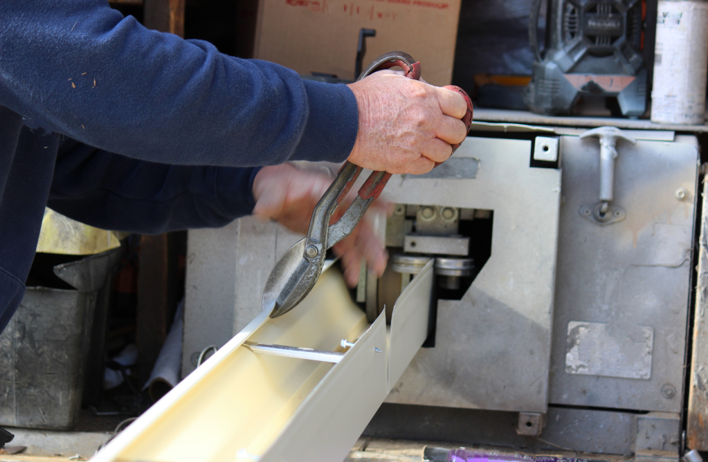 Craftsman using hand plane to smooth wood board in workshop with tools