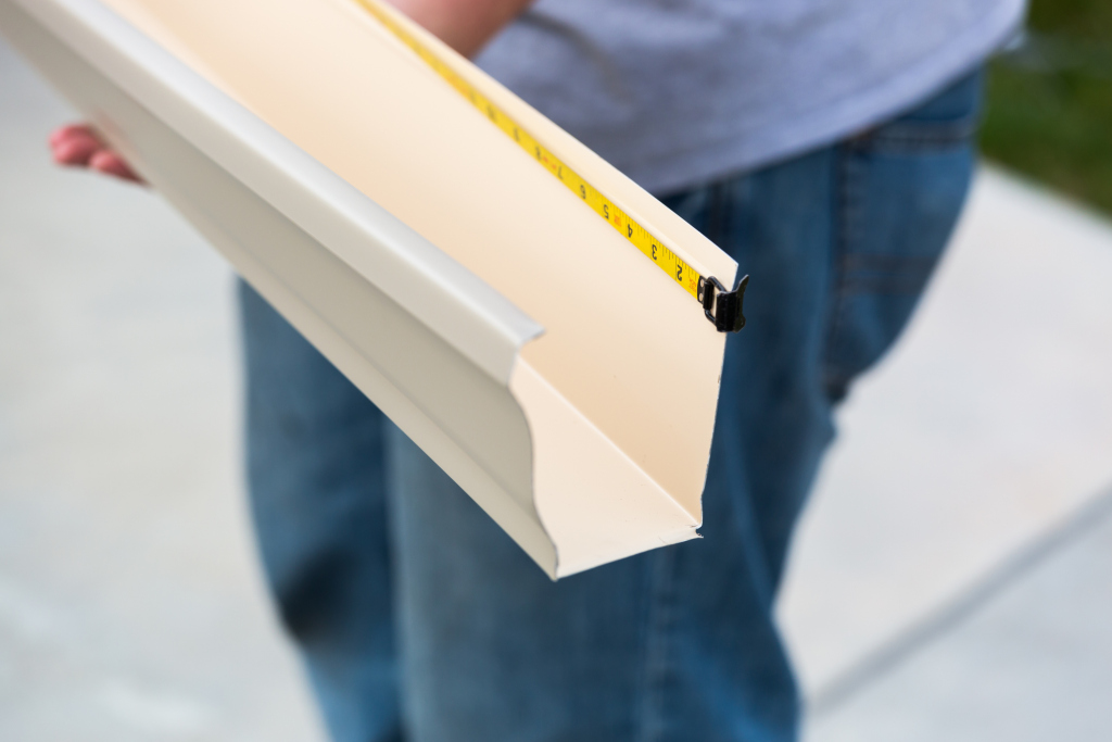 Worker measuring white wooden trim molding with yellow tape measure for installation