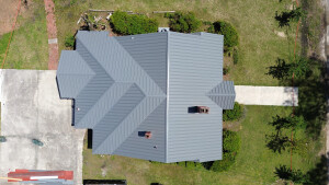 Aerial view of residential house with gray metal roof surrounded by green lawn