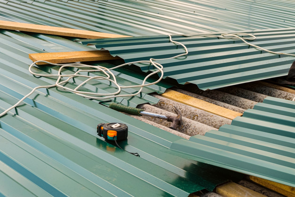 Metal roofing sheets with tools and measuring tape during construction project
