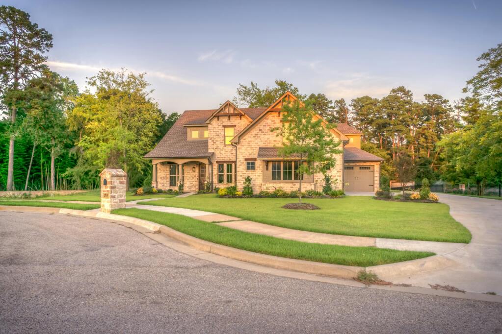 Modern brick house with attached garage and landscaped front yard in suburban neighborhood