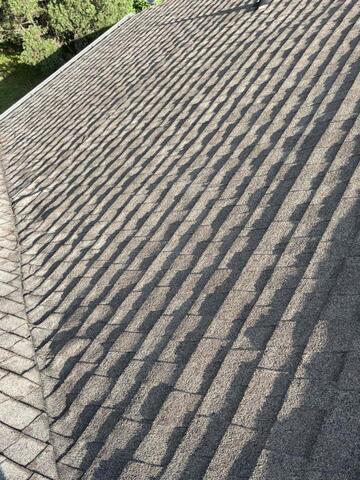 Aerial view of gray asphalt shingle roof with overlapping pattern and shadows