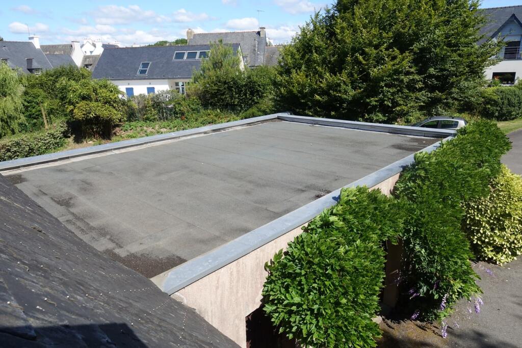 Flat roof construction with concrete foundation surrounded by green landscaping