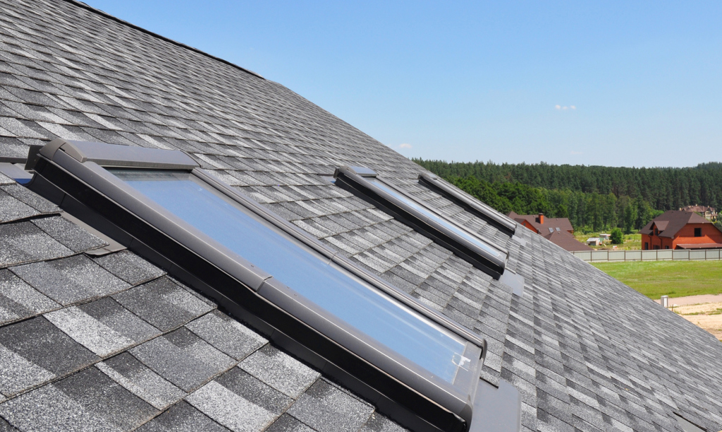 Modern roof skylights installed on gray shingle roof with residential homes visible