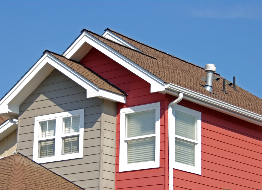 Modern house dormer windows with red and gray siding against clear blue sky