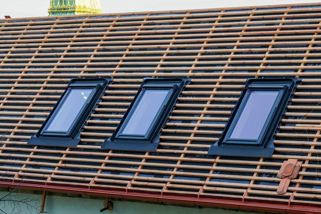 Three roof windows installed on wooden roof structure with exposed battens