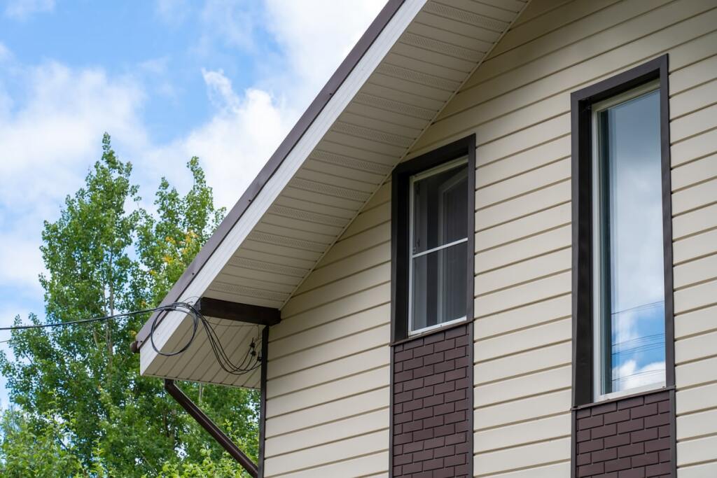 Modern beige vinyl siding house exterior with brick accents and windows